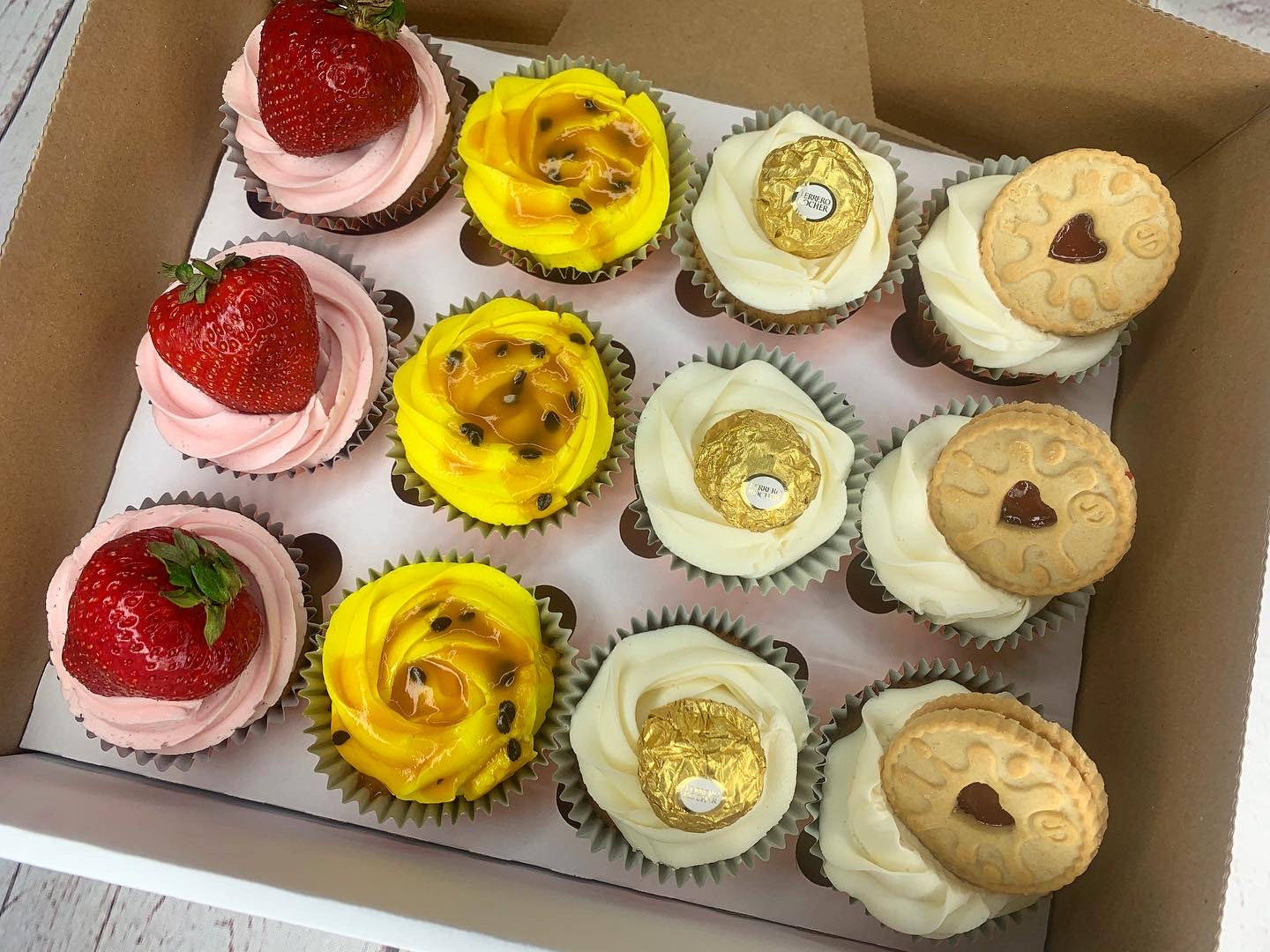 Assorted flavoured cupcakes with fruit, chocolate and biscuit toppings