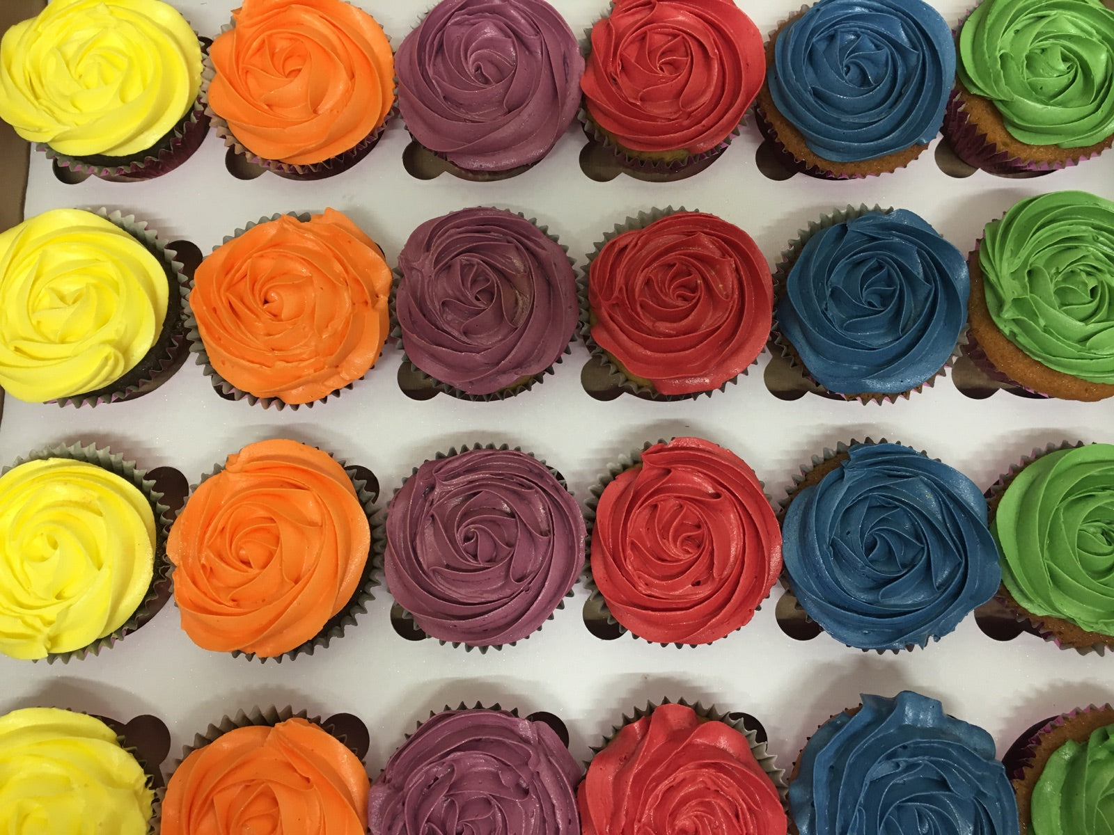 Rainbow frosted cupcakes in a party box