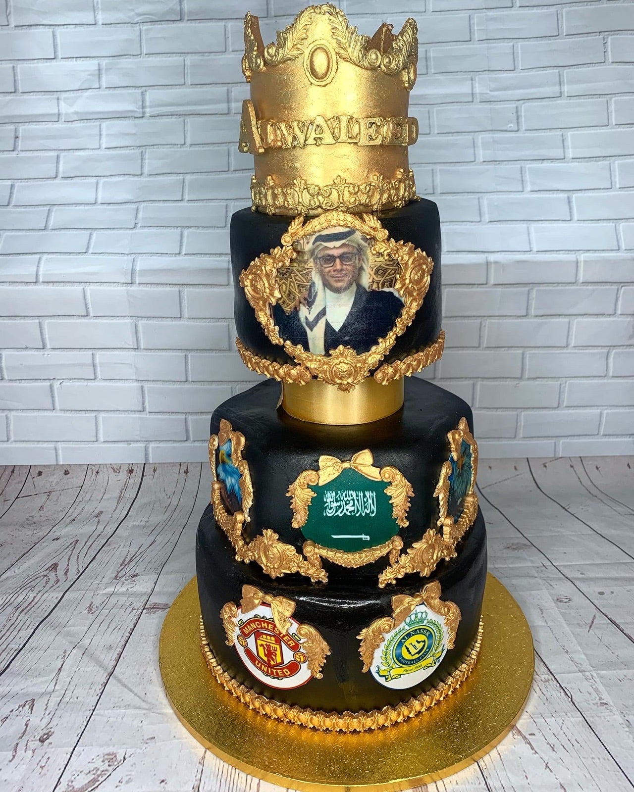 Black and gold tiered birthday cake with a crown topper