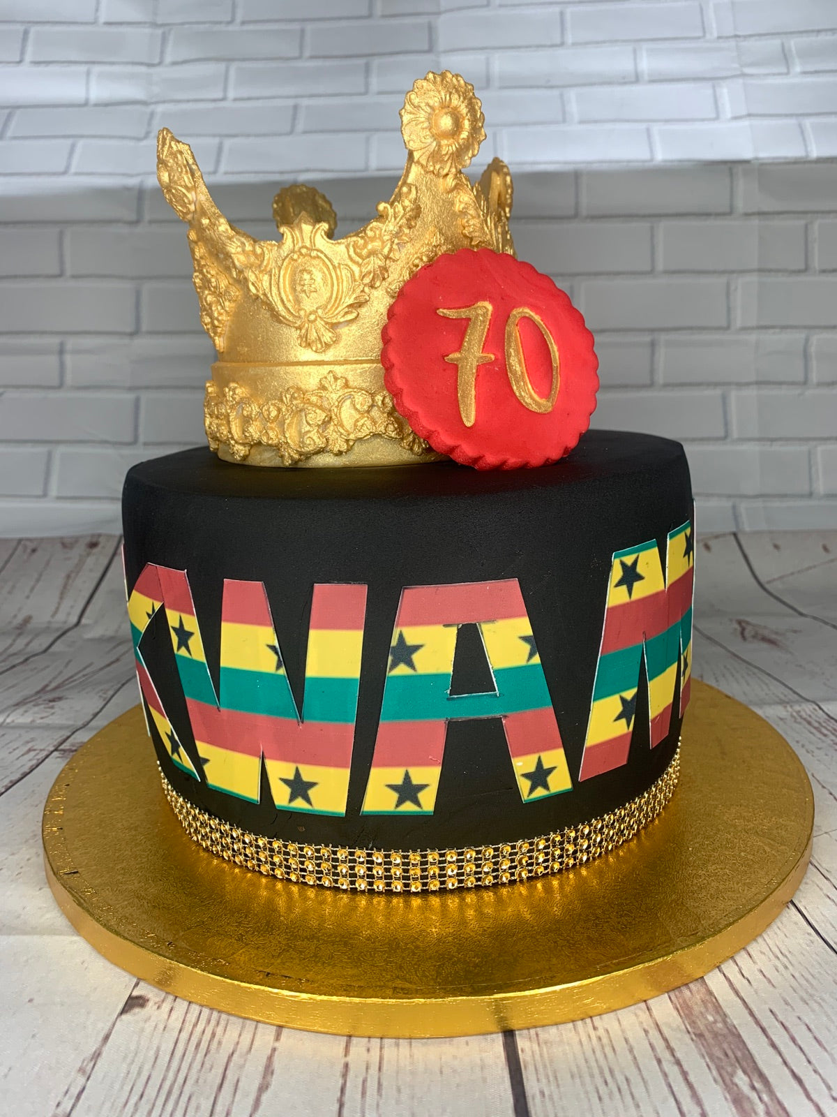 Black birthday cake with Ghana flag lettering and gold crown topper