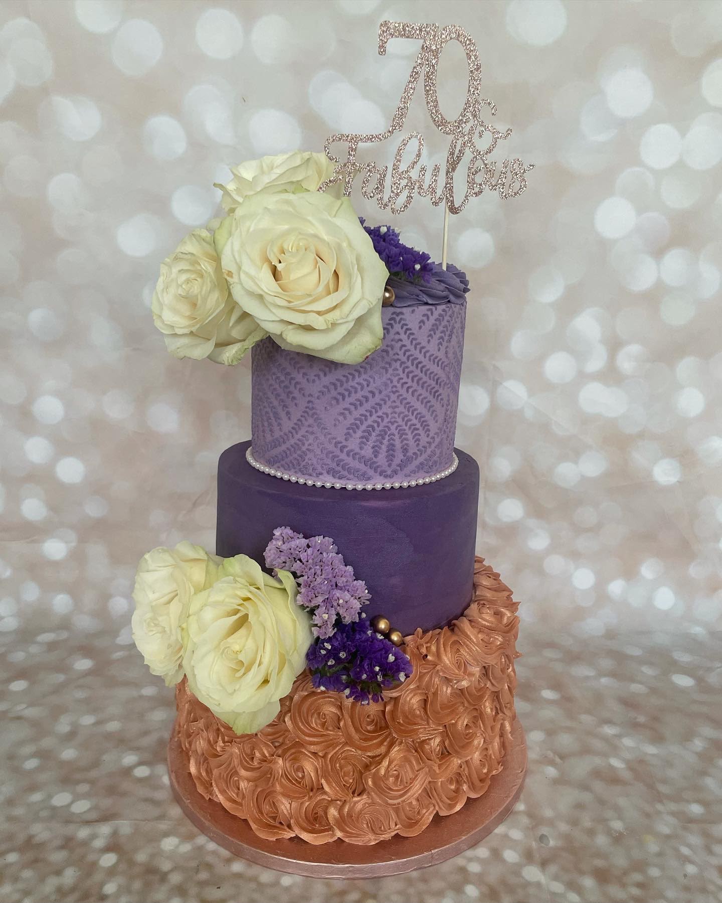 Purple and rose gold 70th birthday cake with white roses