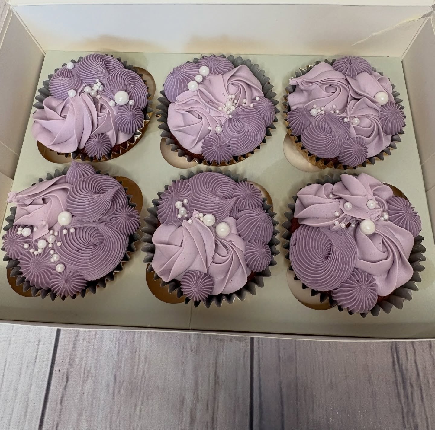 Purple piped cupcakes in a box
