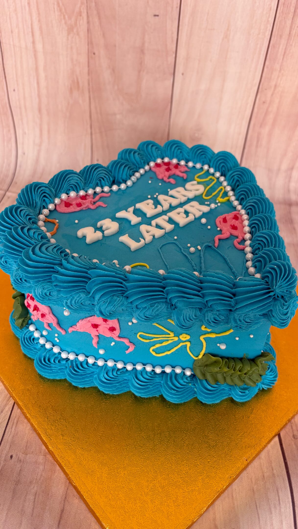 Blue frosted birthday cake with pink cherries